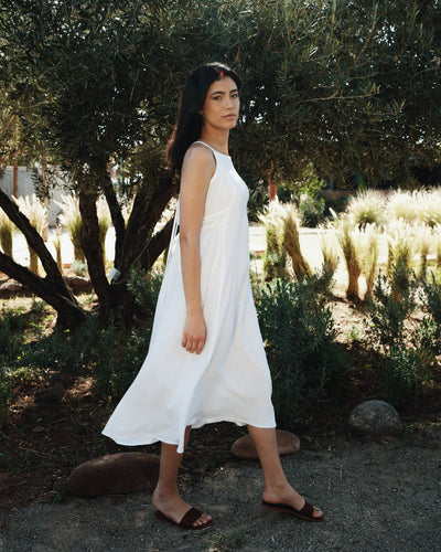 Side view of the versatile white linen dress, highlighting its flowy silhouette and breathable texture.